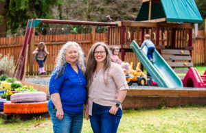 Meredith and Irvina stand in front of the swing set